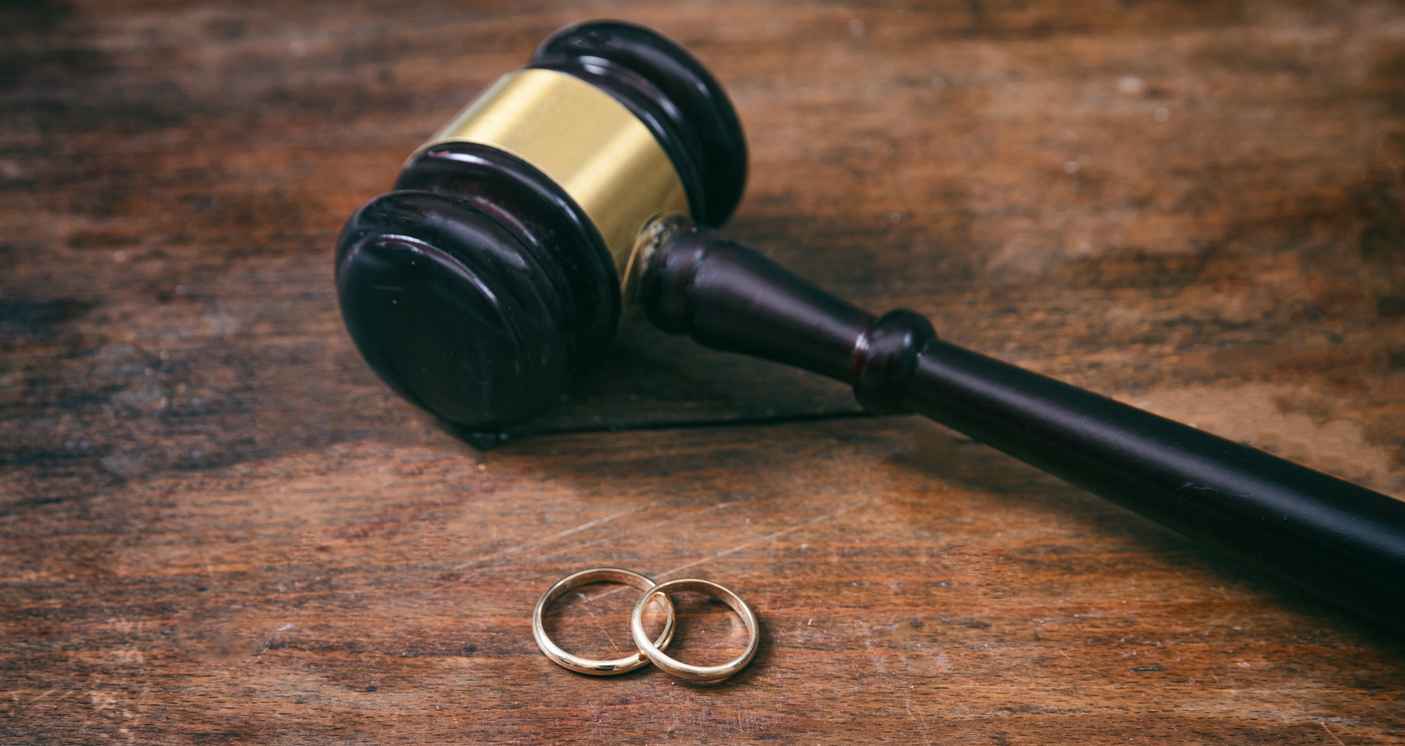 Wedding rings and judge gavel on wood table