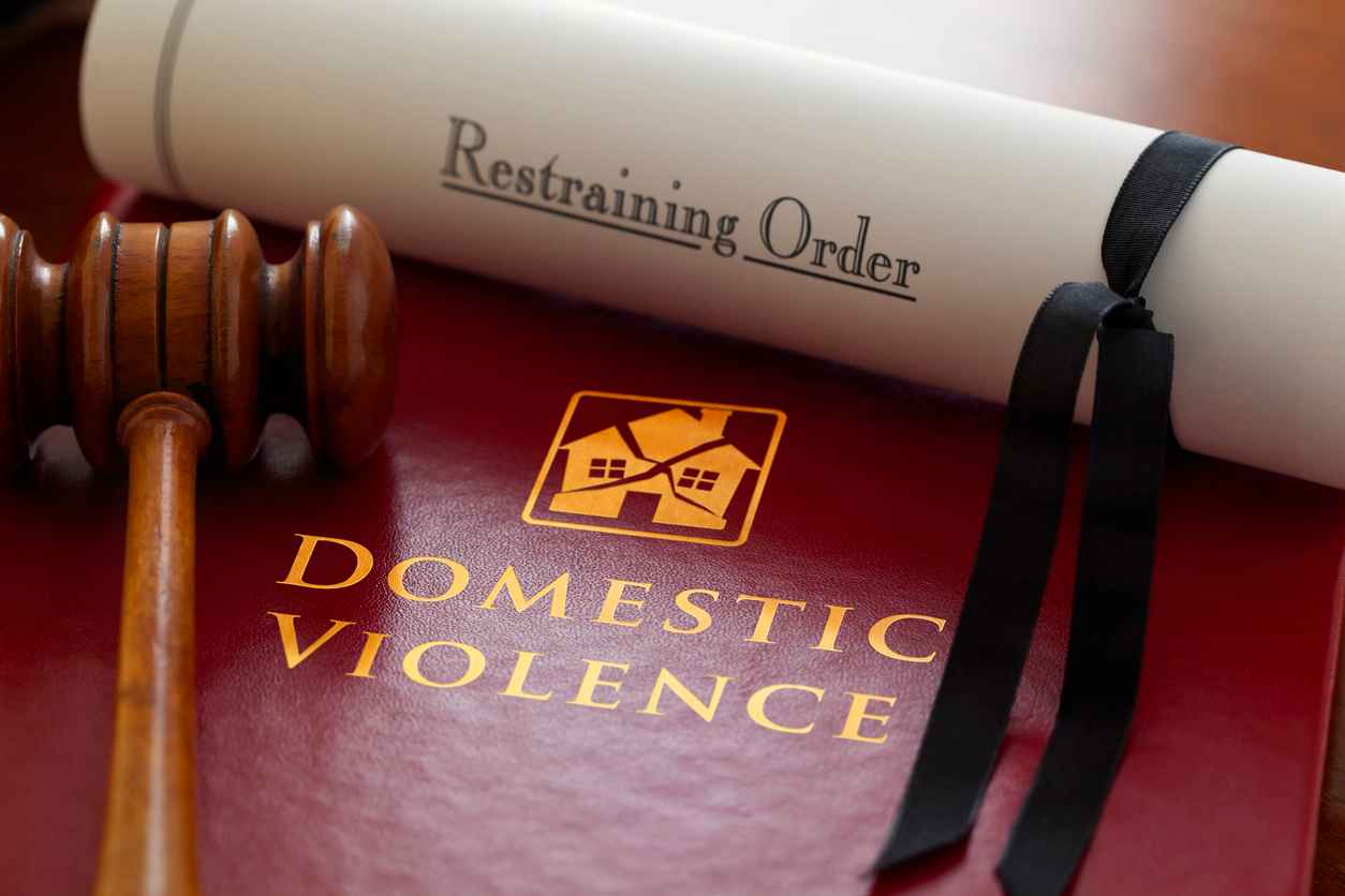 The Law with respect to family related, domestic violence issues. Book of law with a gavel and a Restraining Order. Domestic Violence Laws In New Jersey